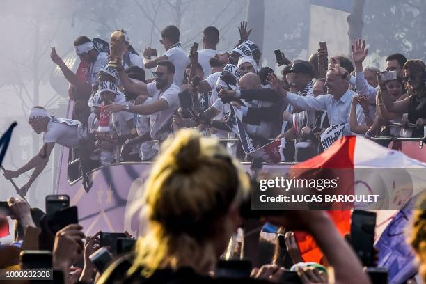 France's fan takes pictures with her mobile phone of France's defender Adil Rami holding the trophy and celebrating with teammates on the roof of a...