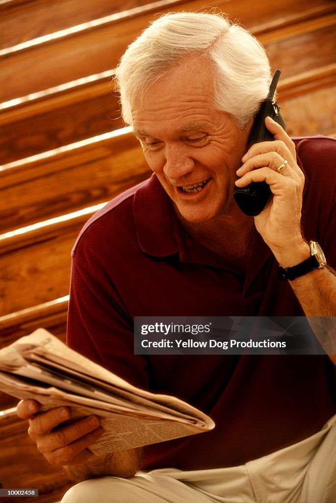 MATURE MAN ON PHONE WITH NEWSPAPER