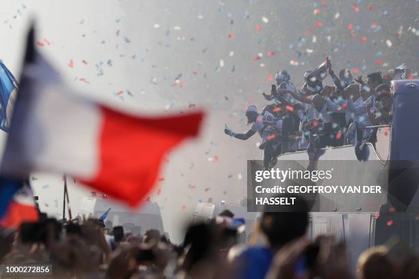 France's fans wave French national flags as they greet and welcome France's national football team players parading down the Champs-Elysee avenue in...