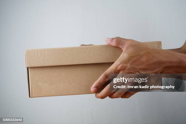 courier in white shirt sending box in studio shot - box hand stock-fotos und bilder
