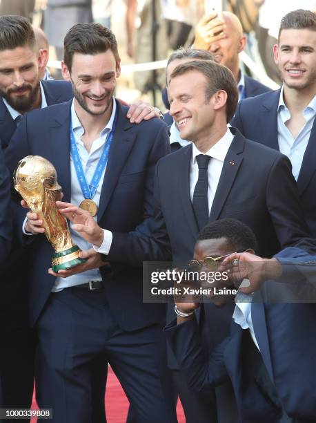 French President Emmanuel Macron poses with Hugo Lloris and the World Cup trophy as he receives France's national football team at Elysee Palace on...