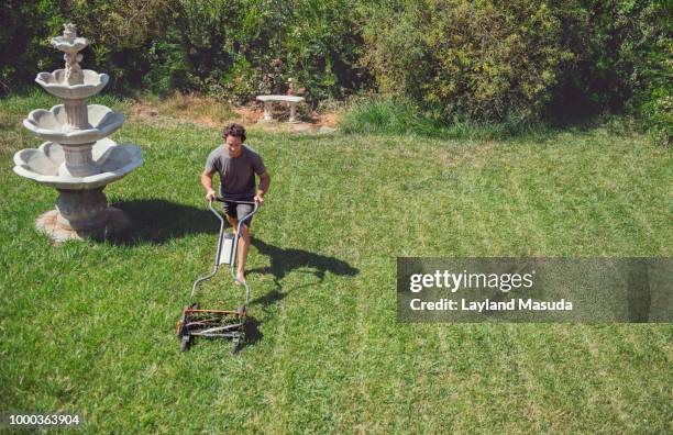 man mowing lawn with push mower - handgrasmaaier stockfoto's en -beelden
