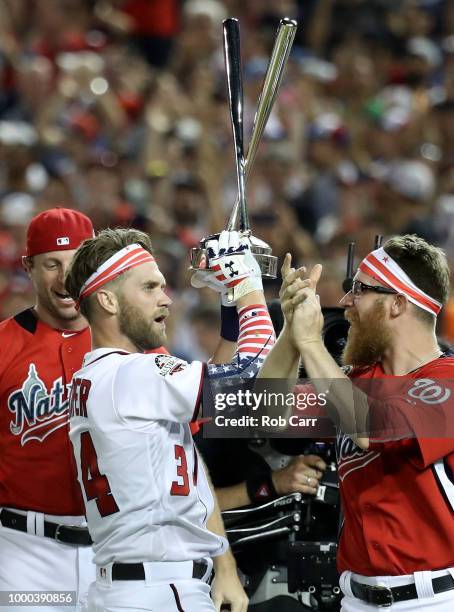 Bryce Harper of the Washington Nationals and National League celebrates with the trophy and teammates Max Scherzer and Sean Doolittle after winning...