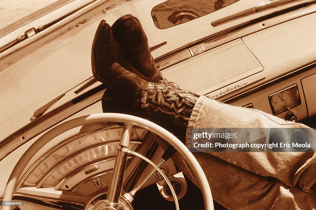 FEET IN WESTERN BOOTS ON DASHBOARD IN SEPIA