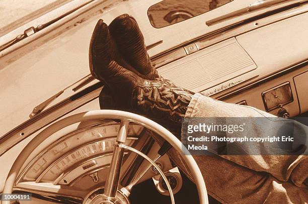 feet in western boots on dashboard in sepia - cowboystövlar bildbanksfoton och bilder