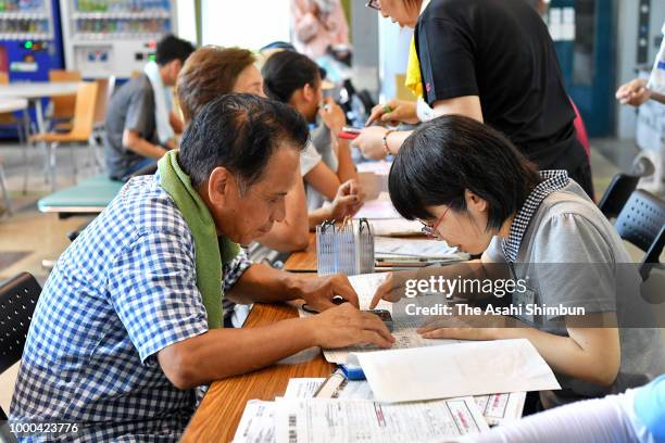 People write the application documents of the disaster certificates on July 16, 2018 in Kurashiki, Okayama, Japan. More than 100 people were treated...