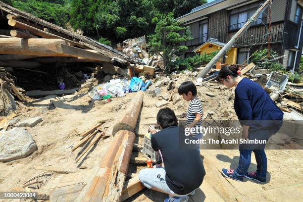 People pray for the victims in front of a house where a mother and two children were killed by a landsldie at Nuwajima Island on July 16, 2018 in...