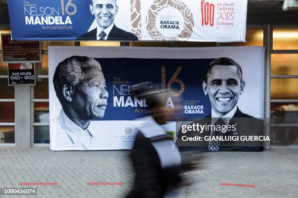 Person walks past a banner depicting former South African leader Nelson Mandela and former US president Barack Obama outside the Wanderers cricket...