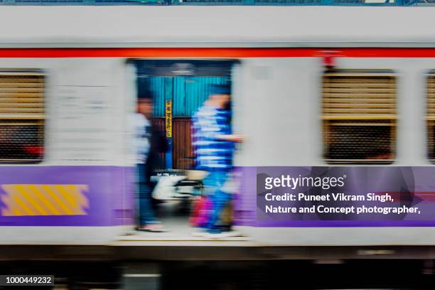 a moving train with passengers onboard at a local train station - mumbai train stock pictures, royalty-free photos & images