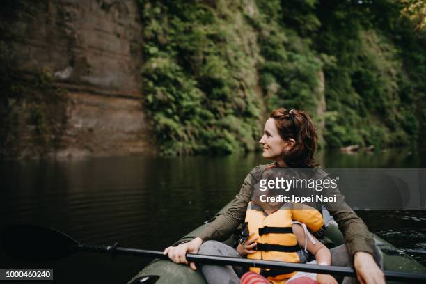 mother and child enjoying view from inflatable boat on river - kayaker woman stock-fotos und bilder
