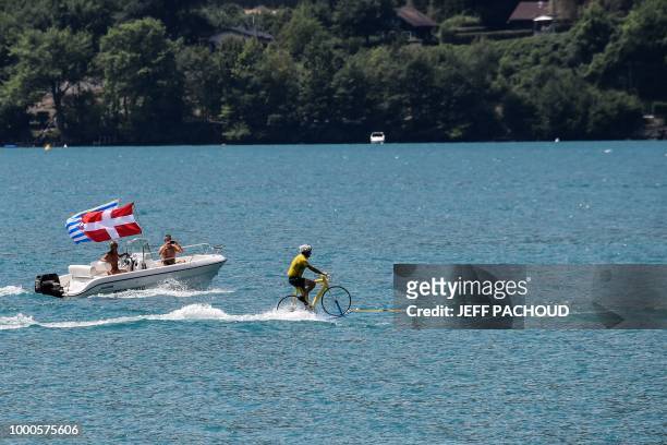 Man wearing a yellow jersey perfoms water skiing on a bicycle, on the Lake of Annecy during the tenth stage of the 105th edition of the Tour de...