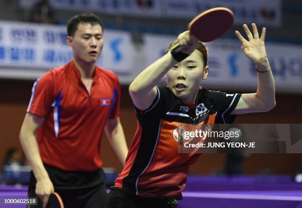 South Korea's Yoo Eun-chong returns the ball as her partner North Korea's Choe Il looks on during their preliminary round match against Spain's...