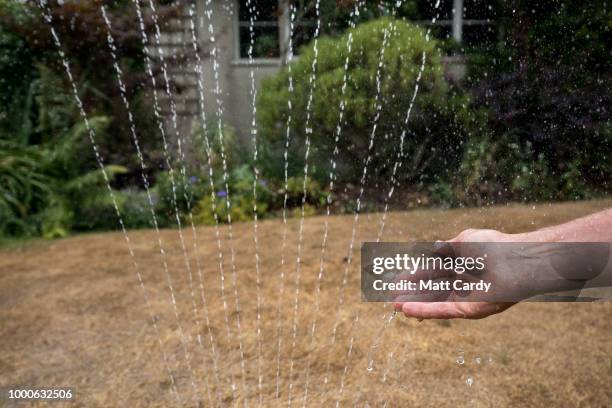 In this photo illustration a man adjusts a hosepipe sprinkler in a garden of a house in the village of Priston on July 17, 2018 near Bath, England....