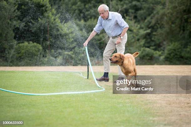 Volunteer groundsman adjusts a hosepipe that is being used to water the wicket at Priston Cricket Club in the village of Priston on July 17, 2018...