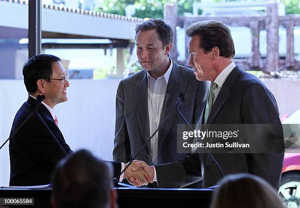 Toyota CEO Akio Toyoda, Tesla Motors CEO Elon Musk and California governor Arnold Schwarzenegger shake hands during a news conference at Tesla Motors...