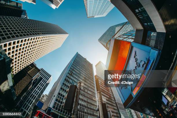 low angle view of contemporary corporate skyscrapers with urban architectural design in busy financial district of hong kong - nasdaq stock pictures, royalty-free photos & images