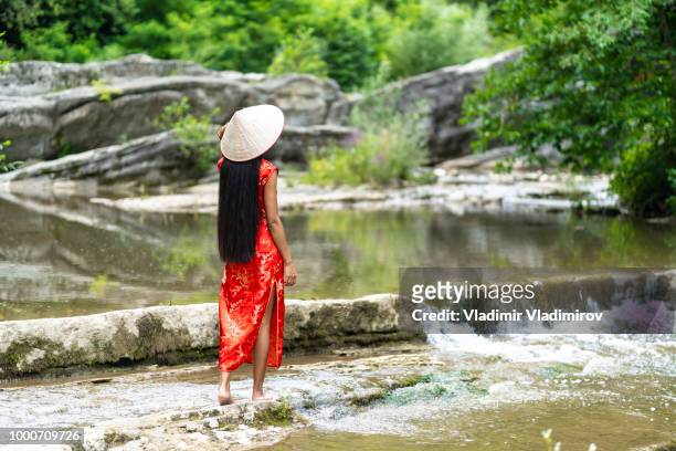 woman in traditional chinese dress walking on river - asian style conical hat stock pictures, royalty-free photos & images
