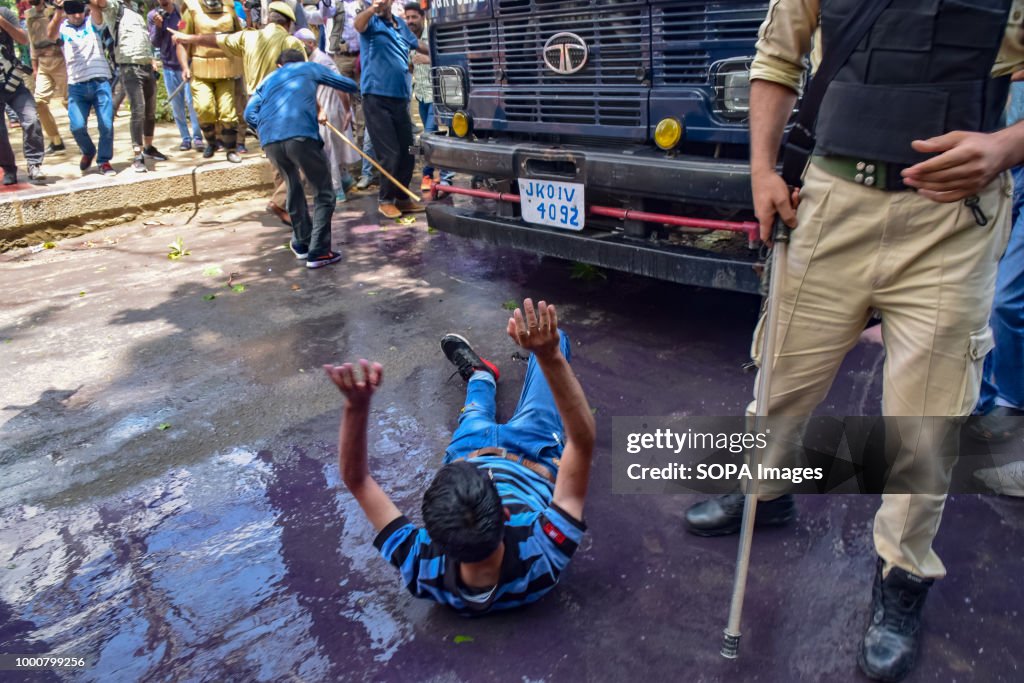 A JK policeman points his baton at a protesting Kashmiri...