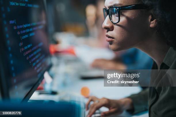 concentrated african american programmer reading computer codes on desktop pc. - graphic design professional stock pictures, royalty-free photos & images