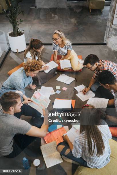 above view of happy college students studying on the floor at campus. - exam preparation stock pictures, royalty-free photos & images
