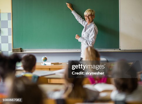 Gelukkig senior docent schrijven een lezing over blackboard op basisschool. Gelukkig senior docent schrijven een lezing over blackboard op basisschool.