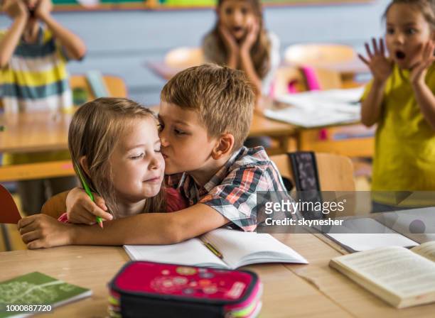 écolier mignon baiser dans la salle de classe, son premier amour. - young boy and girl in love photos et images de collection