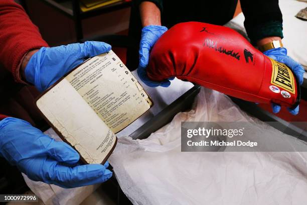 Handlers unveil a boxing glove signed by Nelson Mandela and a pass book he owned at Melbourne Museum on July 18, 2018 in Melbourne, Australia....