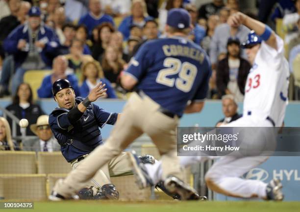 Yorvit Torrealba of the San Diego Padres makes a throw to Kevin Correia as Blake DeWitt of the the Los Angeles Dodgers scores a run off of a wild...