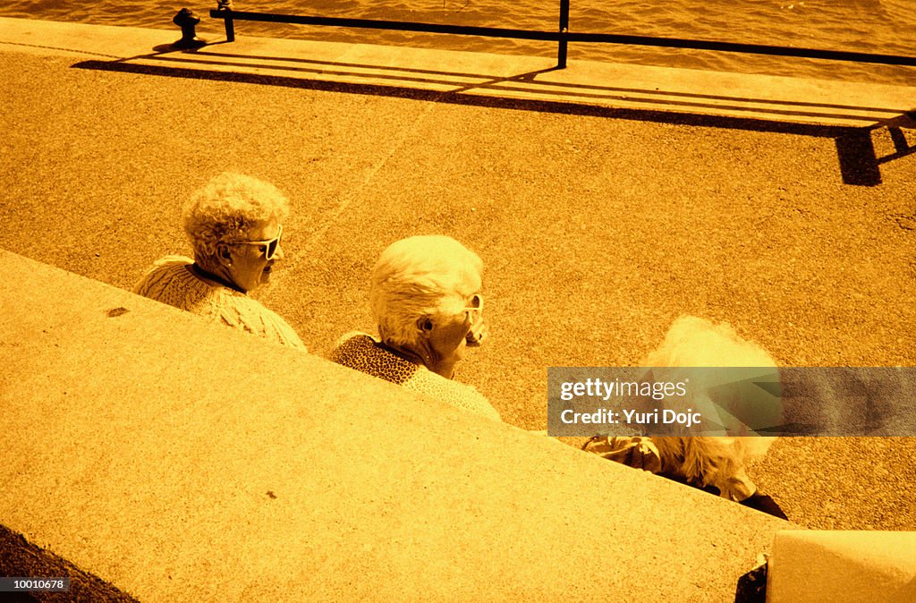 BACK VIEW OF THREE MATURE WOMEN BY WALL