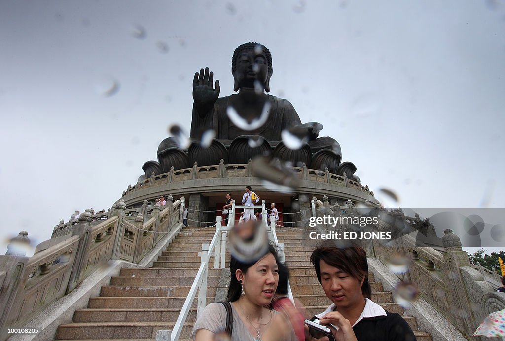 A couple stand before the Tian Tan Buddh