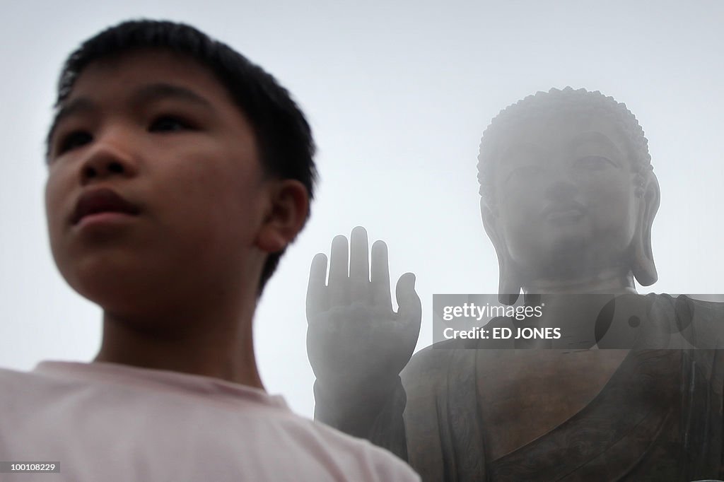 A boy stands before the Tian Tan Buddha