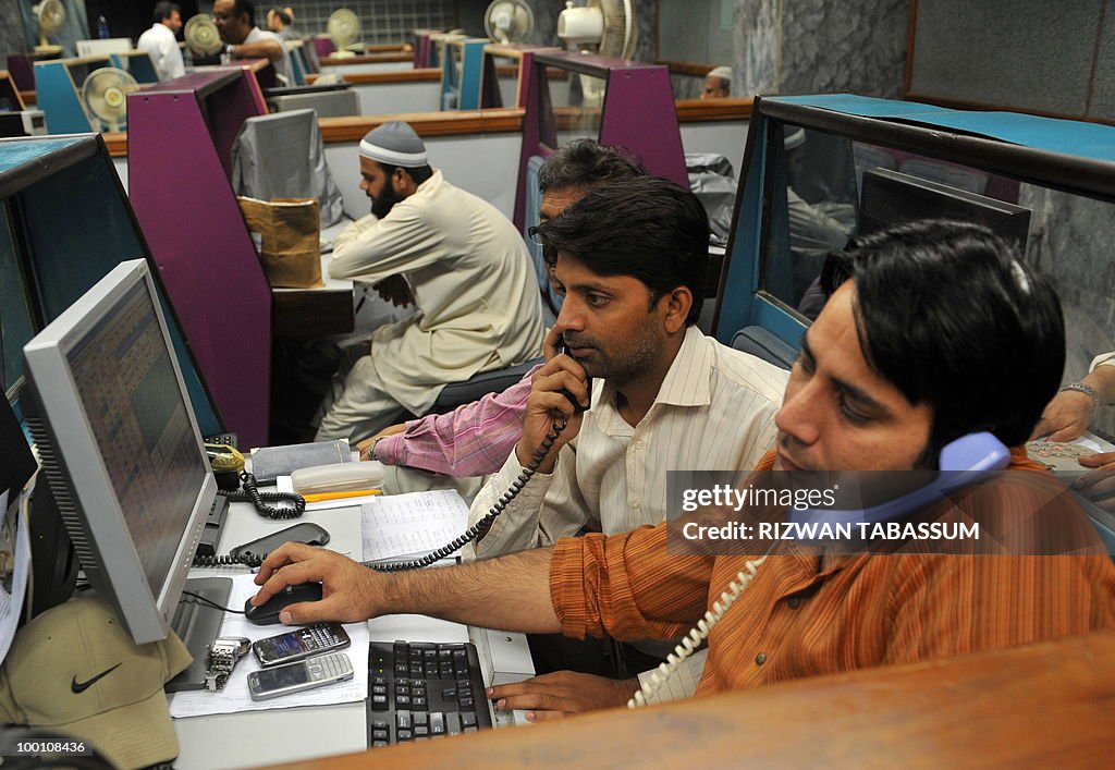 Pakistani stockbrokers talk on phones as