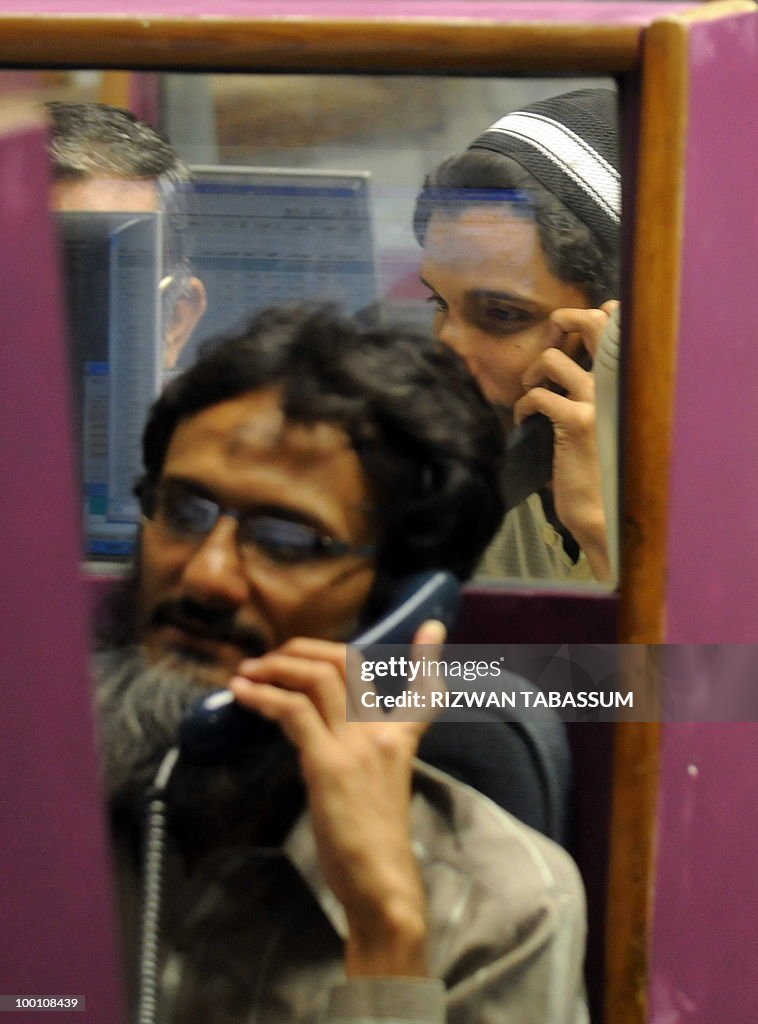 Pakistani stockbrokers talk on phones as