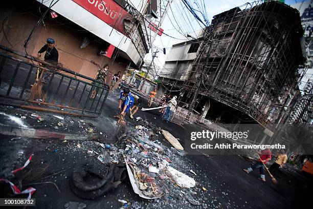 Thai people clean an area of Rama IV after it was attacked during clashes between anti-government protester 'Red shirt' and Thai security forces at...