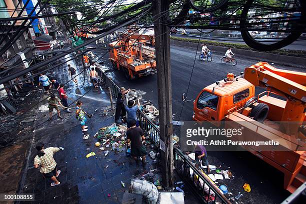 Thai people and workers clean an area of Rama IV after it was attacked during clashes between anti-government protester 'Red shirt' and Thai security...