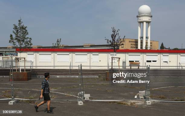 Man walks along the fence surrounding a temporary refugee reception center at the former Tempelhof airport on July 18, 2018 in Berlin, Germany. Local...