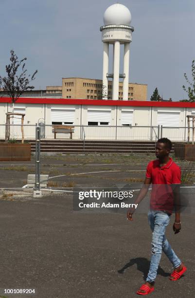 Man walks along the fence surrounding a temporary refugee reception center at the former Tempelhof airport on July 18, 2018 in Berlin, Germany. Local...