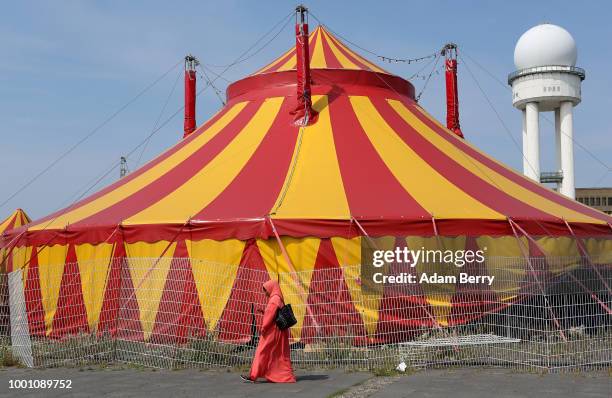 An asylum seeker passes a circus tent next to a temporary refugee shelter at the former Tempelhof airport on July 18, 2018 in Berlin, Germany. Local...