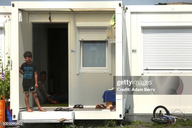 Refugee child stands on the porch of a shipping container in a temporary shelter at the former Tempelhof airport on July 18, 2018 in Berlin, Germany....
