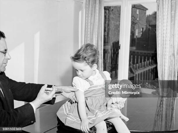 Young patient looks on with trepidation whilst having her polio vaccination, circa April 1959.