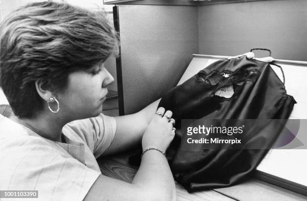 Quality control officer Helen Jones examines a Janet Reger camisole under controlled lighting at the Berlei factory in Merthyr, Wales. September 1984.