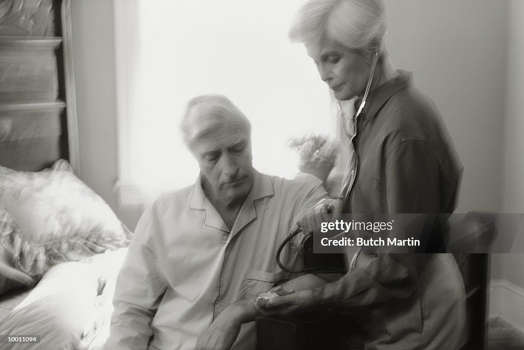 MATURE WOMAN TAKING MAN'S BLOOD PRESSURE