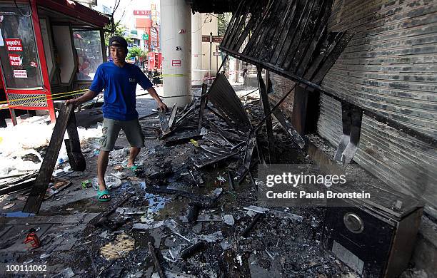 Thai workers clean up the rubble from burnt shops attacked after red shirt protesters set fire to shops taking revenge against the government on May...