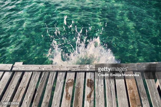 wet footprints on the edge of the wooden dock - jumping into water stock-fotos und bilder