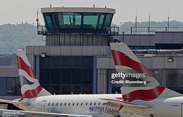 British Airways airplanes sit in front of the air traffic control tower at City Airport in London, U.K., on Friday, May 21, 2010. British Airways Plc...