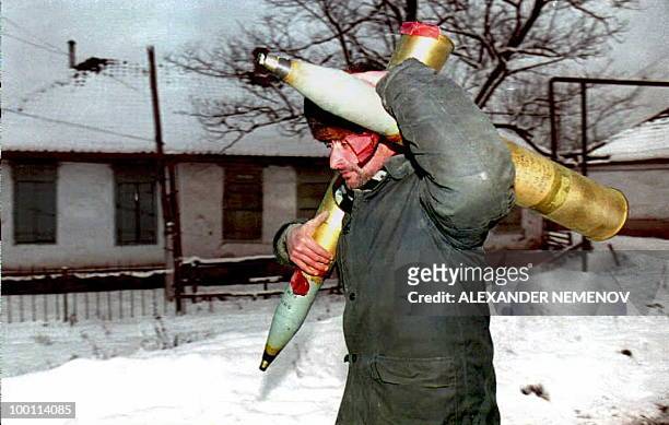 Chechen fighter carries two shells on his way back to his position 26 January 1995, as heavy guns of the Russian forces continue to blast Grozny's...