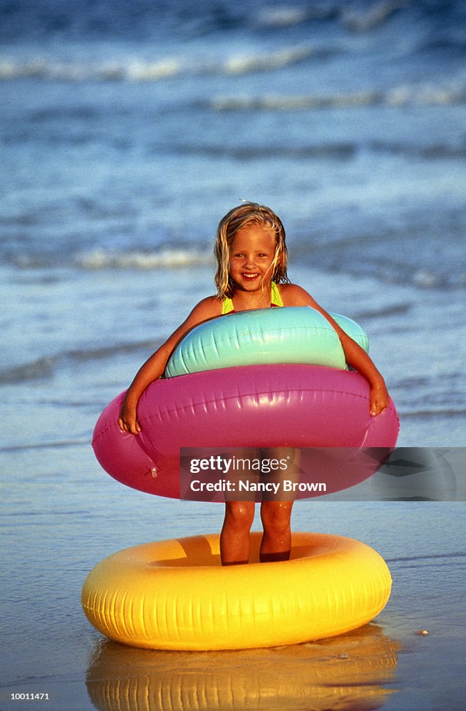 GIRL WITH COLORFUL INNER TUBES ON BEACH