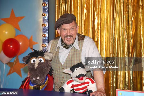 German actor Dietmar Baer with the figures 'Wolle' and 'Pferd' during the 'Alarm im Zirkus' photo call presented by Sesamstrasse on July 18, 2018 in...