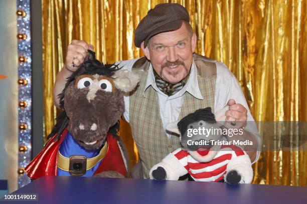 German actor Dietmar Baer with the figures 'Wolle' and 'Pferd' during the 'Alarm im Zirkus' photo call presented by Sesamstrasse on July 18, 2018 in...