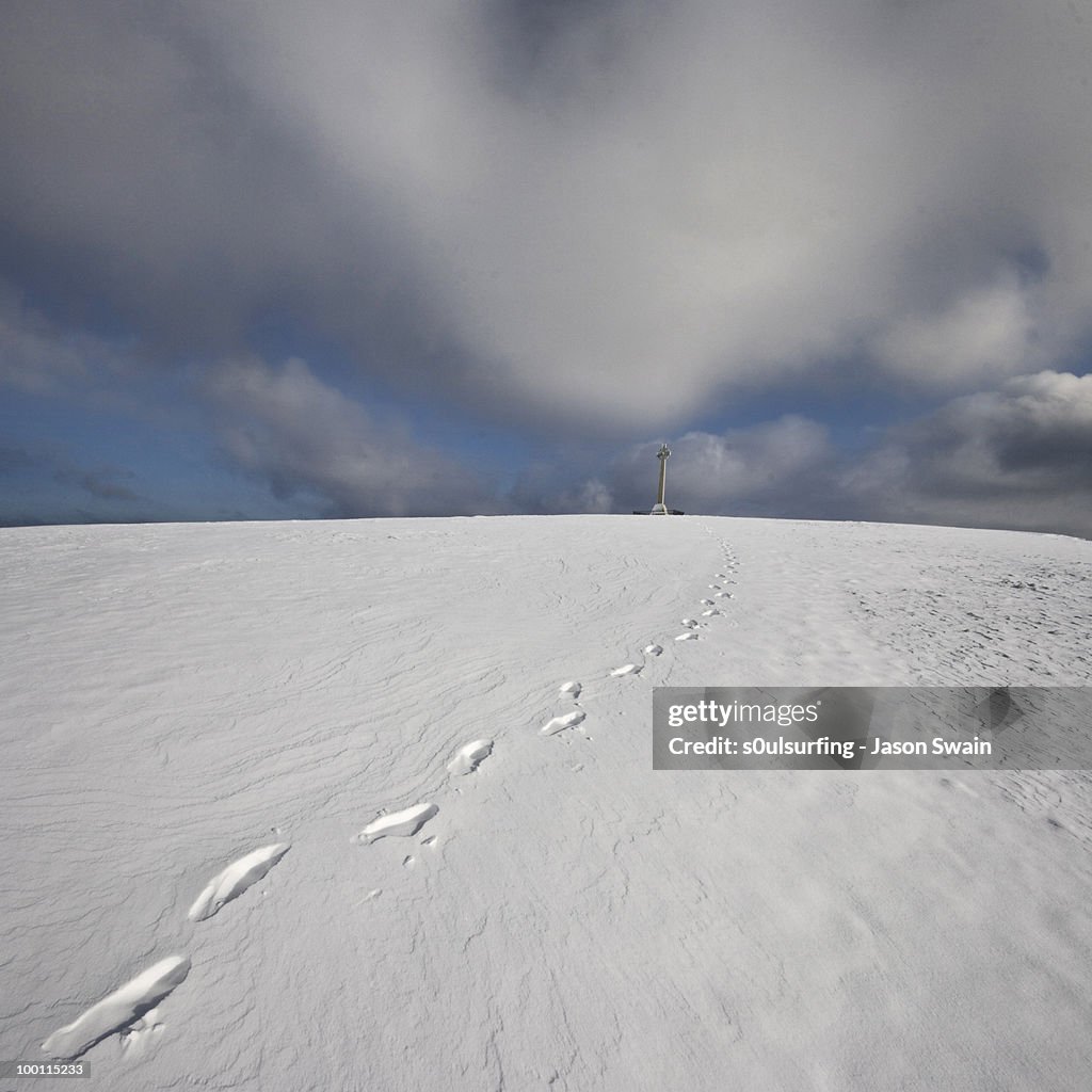 Footprints in snow leading to cross